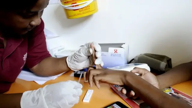 Woman dey hold person finger for HIV/Aids test