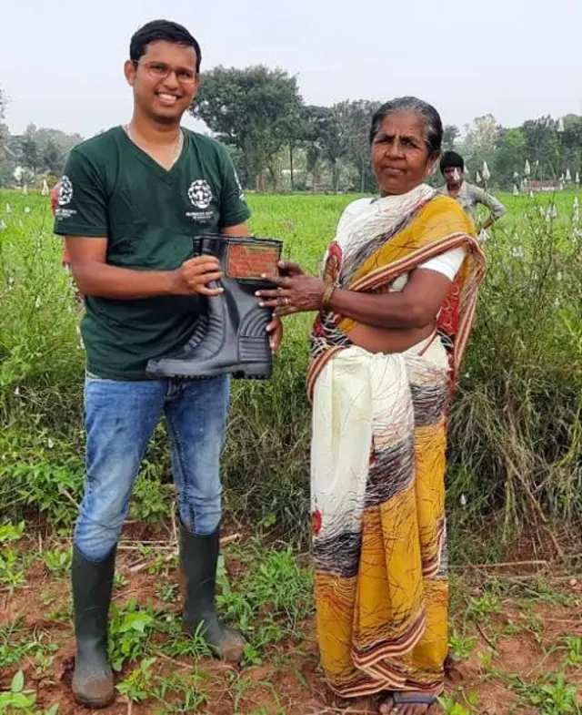 গ্রামে সাপের কামড় থেকে বাঁচার জন্য রাবারের গামবুট দিচ্ছেন এইচএসআই প্রকল্পের কর্মী
