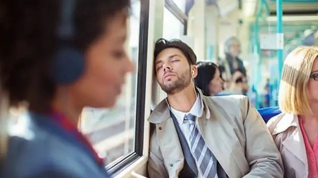 زنی در حال گوش کردن به کتاب صوتی با هدفون در قطار