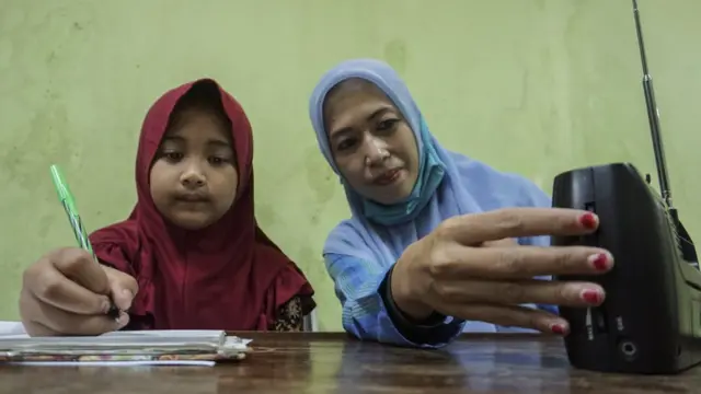 Seorang pelajar didampingi orang tua mengikuti kegiatan belajar mengajar (KBM) melalui siaran radio Lembaga Penyiaran Publik Lokal (LPPL) Radio Kota Batik dari gurunya di Pekalongan, Jawa Tengah, Rabu (2/9/2020)