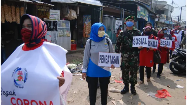 People hold placards during a campaign to promote the government's coronavirus measures in Bandung on 20 April 2020