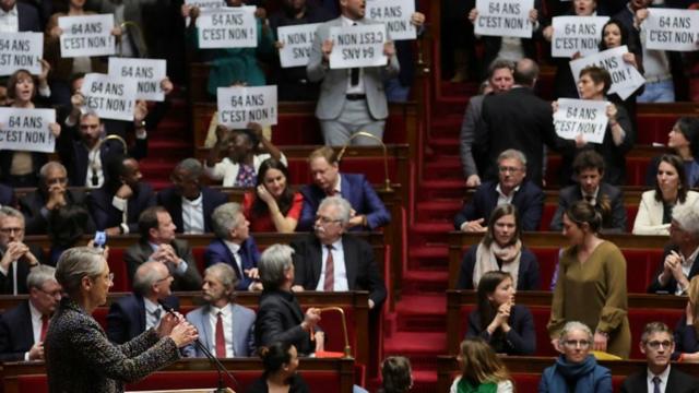 Members of the French parliament hold placards and sing the Marseillaise