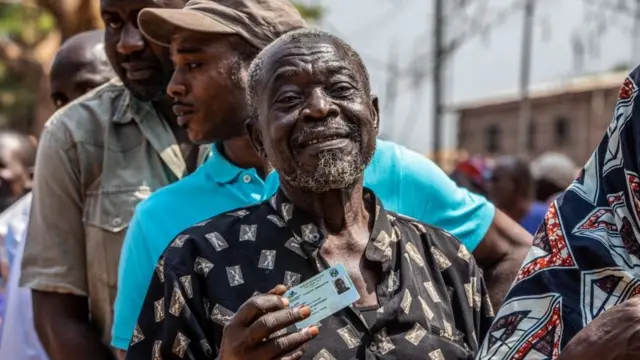 Des électeurs en file avec la tête de file montrant sa carte