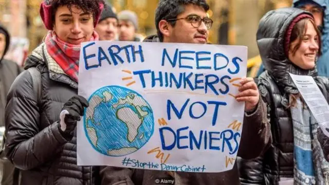 تعدادی زن و مرد با شعار اکثریت دانشمندان بر این باورند که تغییرات آب و هوایی امروز بوسیله انسان ایجاد می‌شود