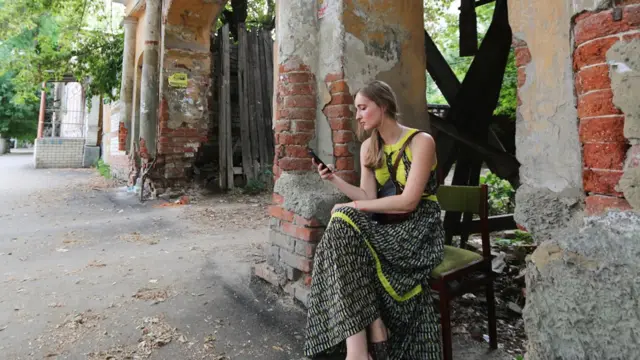 Дизайнер среды Арина Кузьмина сидит у полуразрушенных ворот неподалеку от набережной Космонавтов