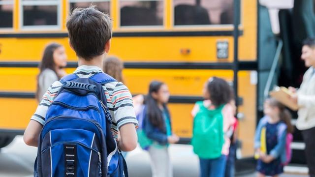 Criança caminha para o ônibus escolas