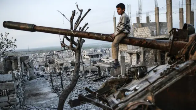 A Syrian Kurdish boy sits on a destroyed tank in the Syrian town of Kobane, also known as Ain al-Arab, on March 27, 2015.