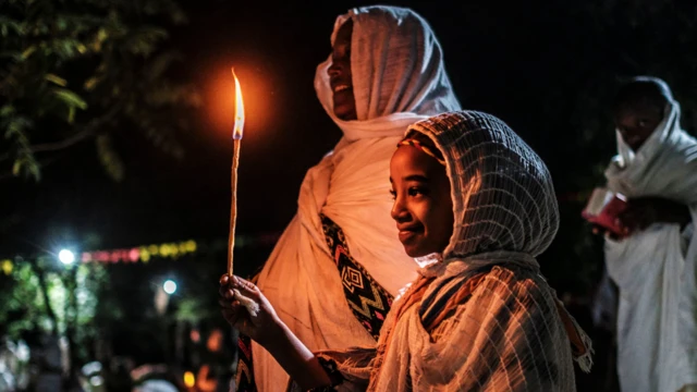 A woman and girl holding at candle at the Fasilides Bath during Timket in Gondar, Ethiopia - Wednesday 19 January 2022