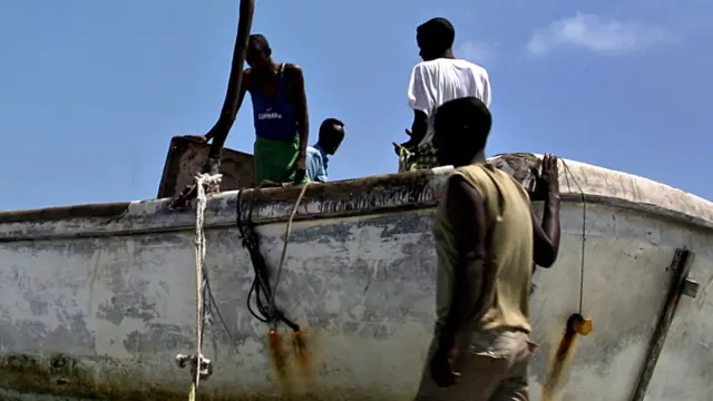 Un grupo de hombres junto a un barco.