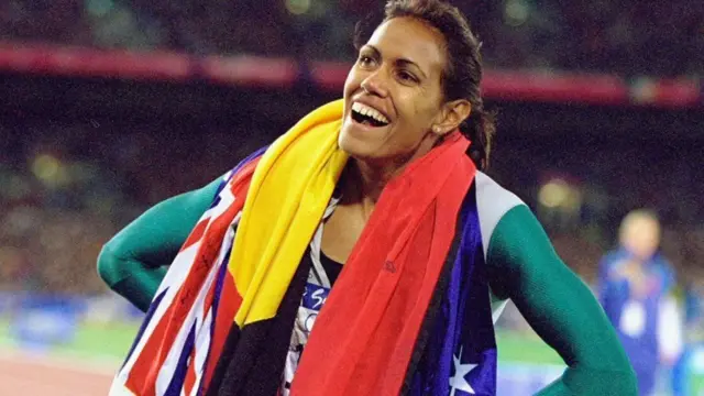 Cathy Freeman oo ku dabaaldagaysa calanka Aboriginal iyo kan Australia ka dib markii ay bilad dahab ah ku guleysatay 2000 magaalada Sydney