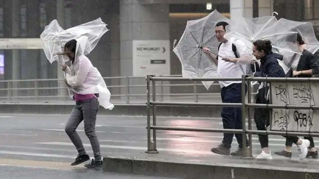 Peatones en Tokio luchan con sus paraguas o sombrillas contra el viento y la lluvia.