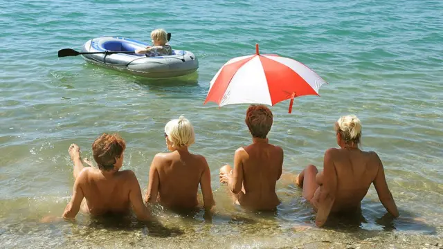 Mujeres desnudas tomando el sol a la orilla de un lago en Alemania observan a un niño en una balse