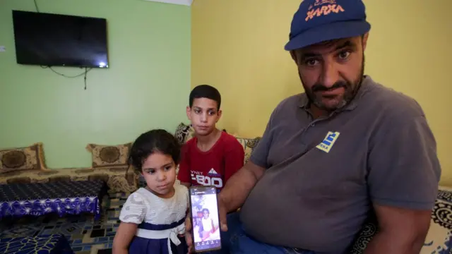 Amar, father of Algerian boxer Imane Khelif, sits with his children as he shows a picture of Imane when she was young, inside his house, in Tiaret province, Algeria August, 2, 2024. REUTERS/Ramzi Boudina TPX IMAGES OF THE DAY