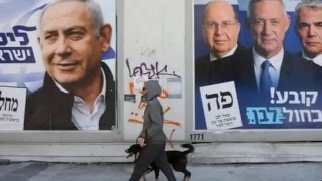 चुनाव के पोस्टर के सामने गुजरता एक व्यक्ति