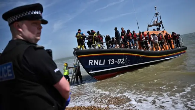 Um policial na frenteroleta vendaum barco da polícia carregado com imigrantes ilegais