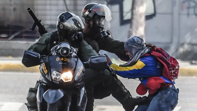 Dos agentes agarran a un manifestante