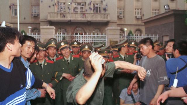 A university student demonstrator throws a rock at the U.S Embassy in Beijing May 9, 1999. Protests have erupted in a dozen or so major Chinese cities, drawing tens of thousands of angry citizens onto the streets. State media has fanned the fury by saying that the NATO bombing of the Chinese Embassy in Belgrade was a deliberate act of aggression.