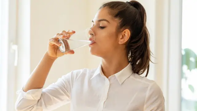 Jeune femme buvant un verre d'eau
