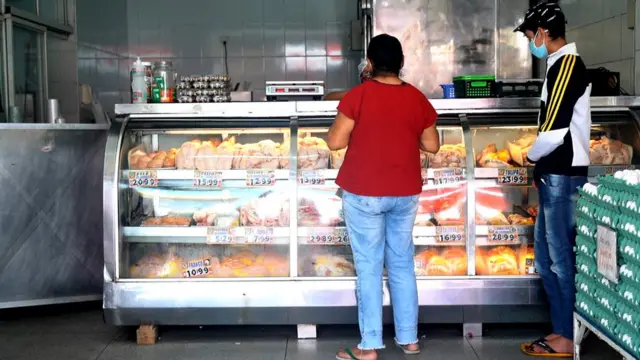 Lindinalva comprando carcaças e pele de frango ao lado do neto dela