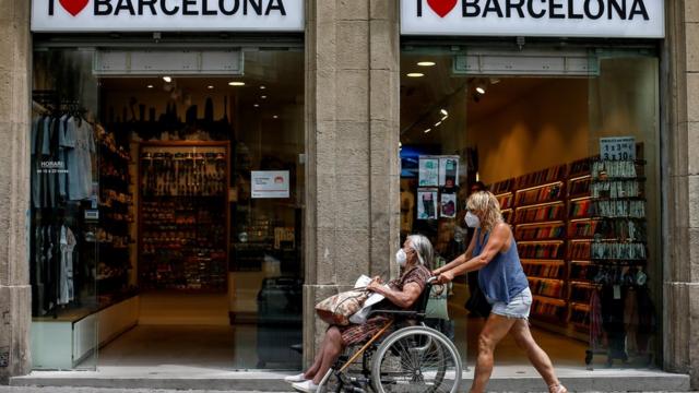 женщина везет в коляске пожилую женщину в Барселоне