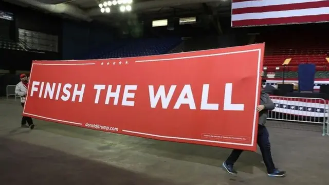 Cartaz com a frase 'finish the wall' (termine o muro)