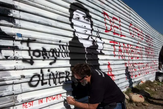 Manuel Oliver trabaja trabaja en un mural en la valla fronteriza entre EE.UU. y México que dice "Del otro lado también matan a nuestros hijos". Tijuana, México, 19 de diciembre, 2018.
