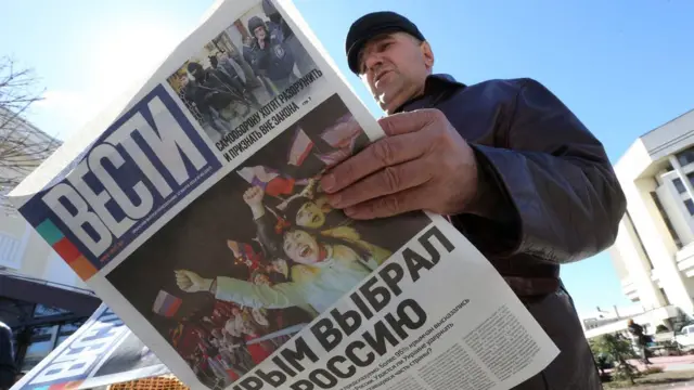 Hombre lee un periódico celebrando la anexión de Crimea
