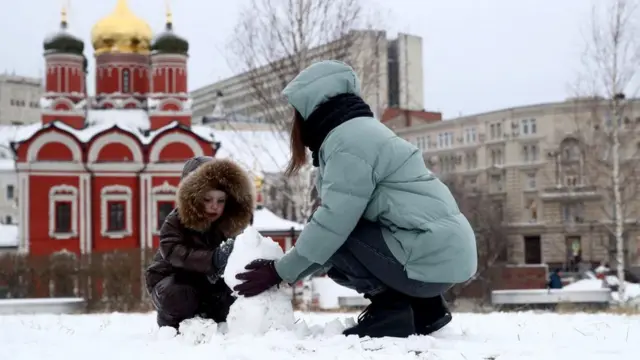 A woman and a child build a snowball in Moscow