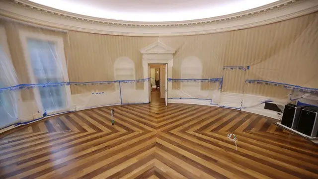 The Oval Office sits empty and the walls are covered with plastic sheeting during renovation work