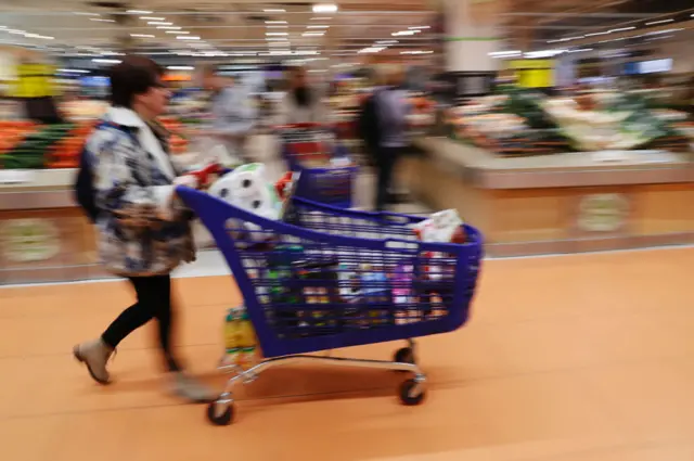 Mujer con carrito en supermercado.
