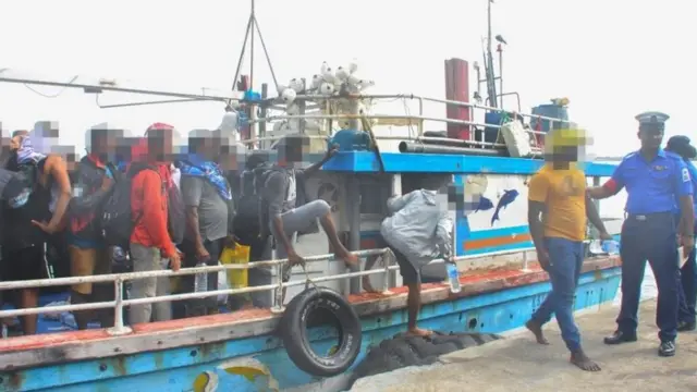 People get off a boat which has been stopped by the Sri Lankan navy