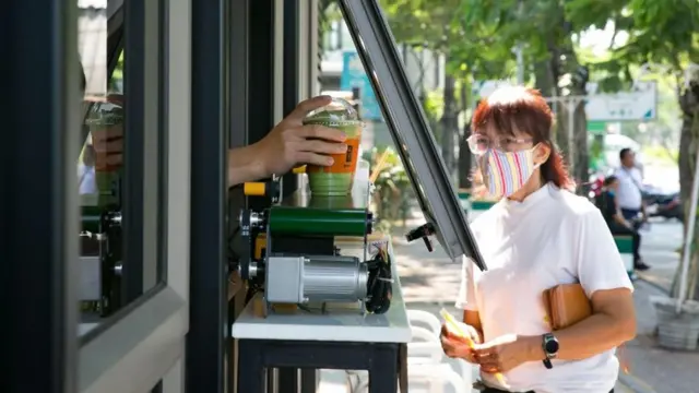 این مغازه در تایلند برای تحویل نوشیدنی به مشتری از تسمه نقاله استفاده می‌کند تا فاصله‌گذاری اجتماعی را رعایت کرده باشد