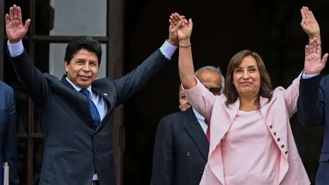 Pedro Castillo e Dina Boluarte acenam com os braços dados e sorrindo