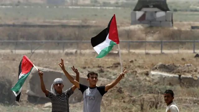 गज़ा में फलस्तीनी झंडे के साथ प्रदर्शन करते युवक