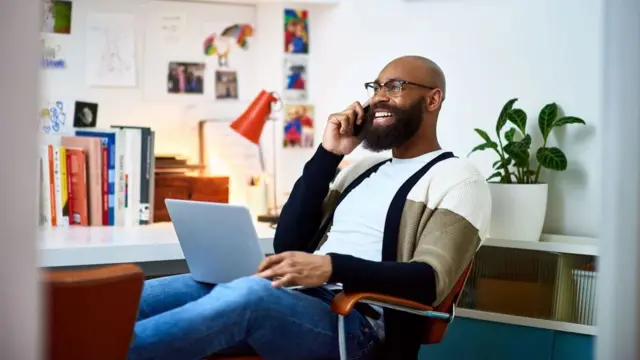 Homem trabalhandoaposta roletinhacasa no telefone com laptop no colo