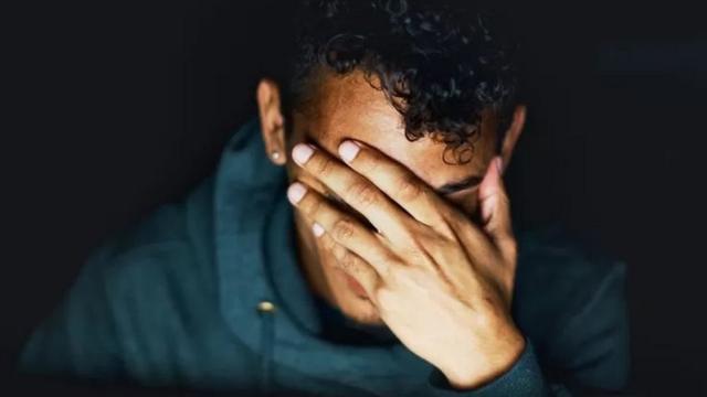 Jovem triste e com a mão no rosto