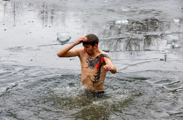 Mladić se krsti pre nego što će zaroniti u vodu u gradu Alčevsku na istoku Ukrajine