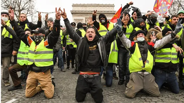 Des "gilets jaunes" font le signe de victoire, face aux policiers.