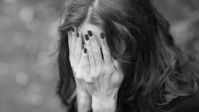 женщина, закрывшая лицо руками