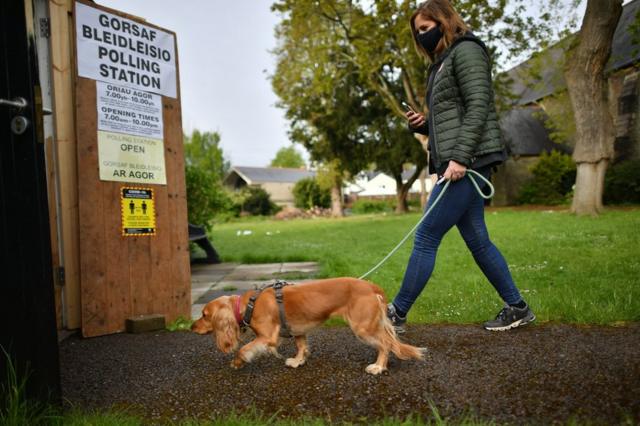 A dog and its owner walk into a polling station in Cardiff, Wales