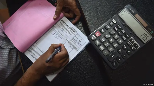 An Indian shopkeeper prepares a bill for a customer at his shop in New Delhi on August 3, 2016.