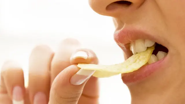 Una mujer comiendo papas fritas.