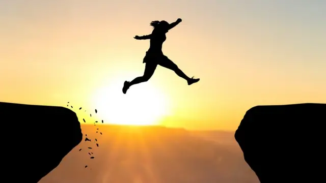 Mujer saltando entre dos rocas