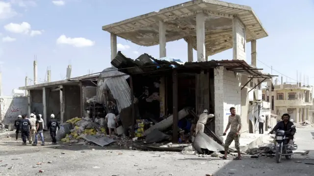 People gather at a site hit by what activists said was an air strike by forces of Syrias President Bashar al-Assad, in Hesh village in the southern countryside of Idlib on 27 September 2015
