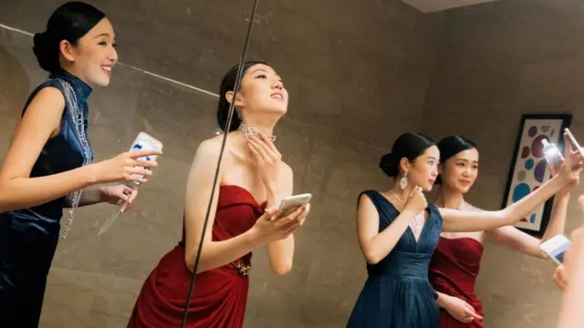 عارضات أزياء شابات في الصين يلتقطن لأنفسهن صورا ذاتية أثناء أحد عروض الأزياء