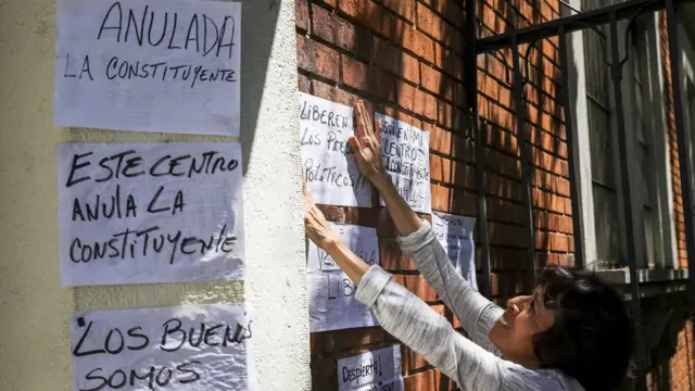 Una opositora cubre con carteles de protesta un centro de votación en Caracas.