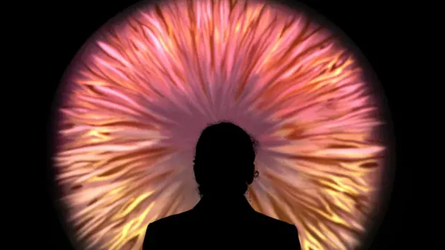 Contorno de una mujer mirando una proyección abstracta similar al iris de un ojo.