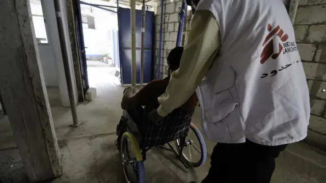 رجل يدفع مصابا على مقعد متحرك