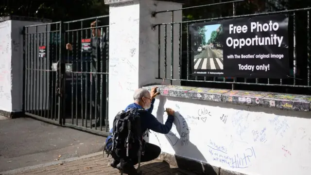 Un hombre escribe en el muro de los estudios de Abbey Road, en Londres