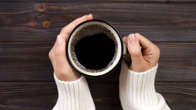 Una joven tiene entre sus manos una taza de café